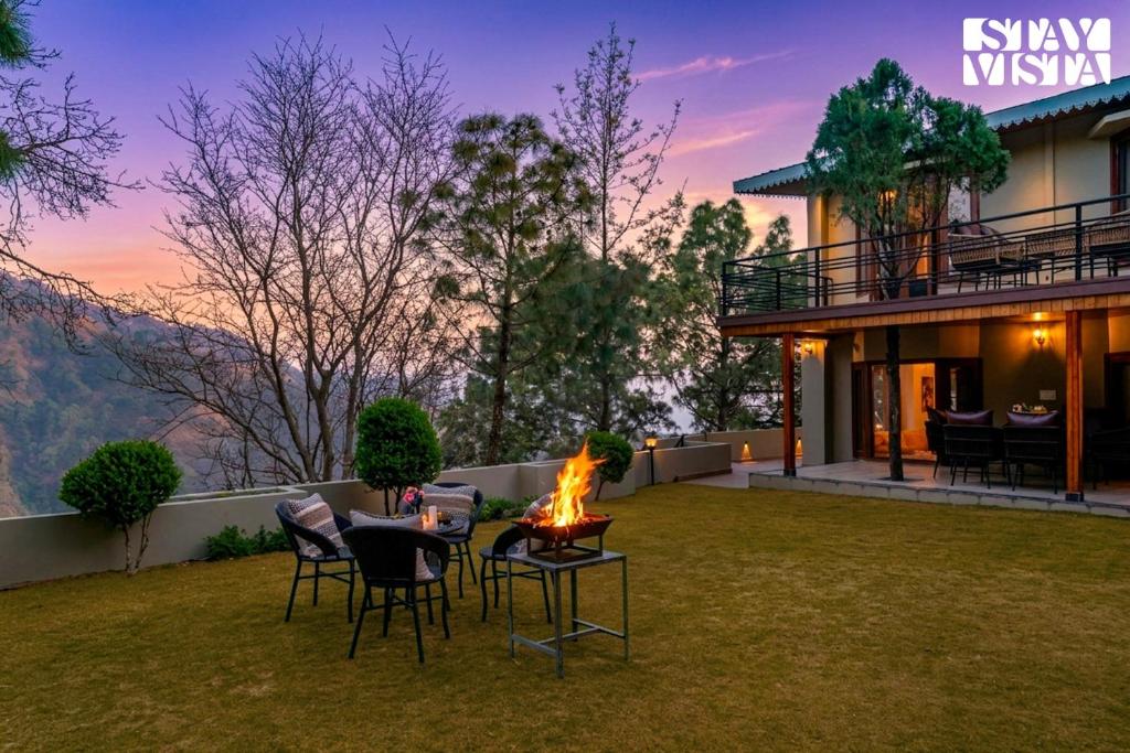 a backyard with a table and chairs and a fire pit at StayVista at Cedar Crest Villa with Bonfire, Valley View in Kasauli