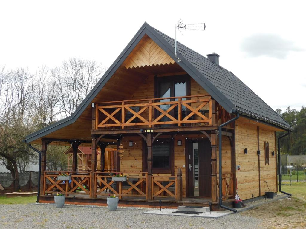 a large wooden cabin with a black roof at Zielone Rykowisko - Myśliwski domek całoroczny in Blizów