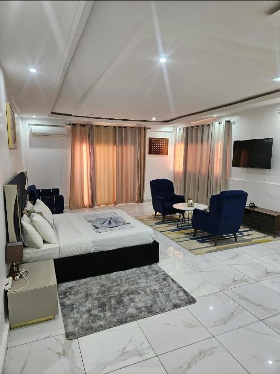 a bedroom with a bed and chairs and a tv at Hotel liberté 6 in Dakar