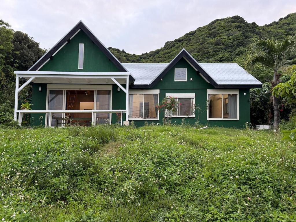 a green house on top of a grass field at Green Rabbit House by private beach in Ishigaki Island