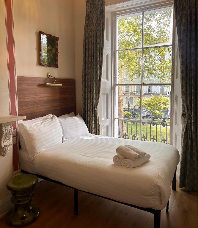 a bed with two towels on it in front of a window at The Norfolk, Paddington in London