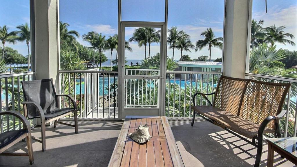a porch with chairs and a table with a cat on it at 406 Mariners Club in Key Largo