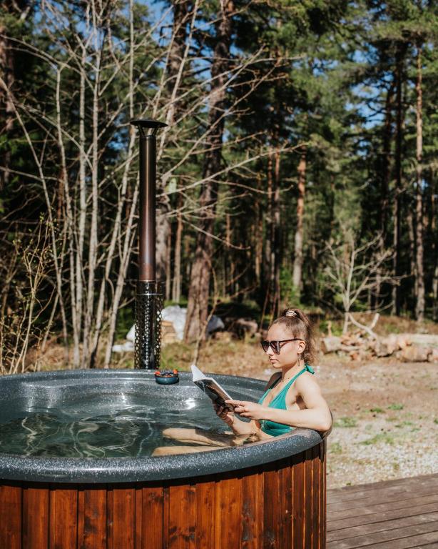 a girl sitting in a hot tub reading a book at Üleoja Pesa in Kloogaranna