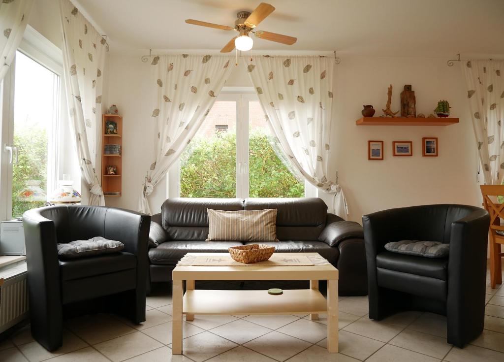 a living room with two black leather couches and a table at Villa Pepita in Kaltenhof