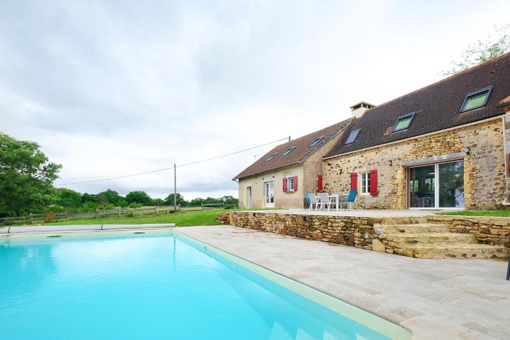 a house with a swimming pool in front of a house at Gite de l'Egal in Le Buisson de Cadouin