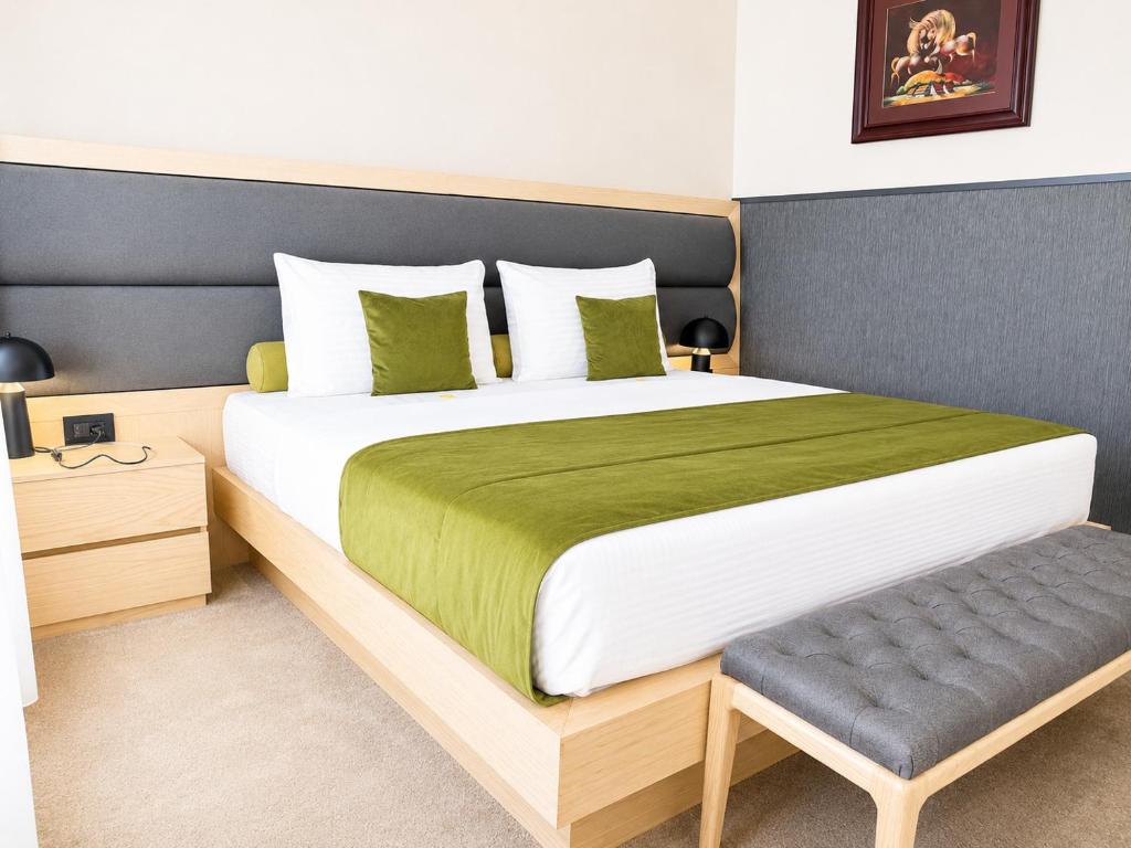 a bedroom with a large bed with a green blanket at Atera Business Suites in Belgrade