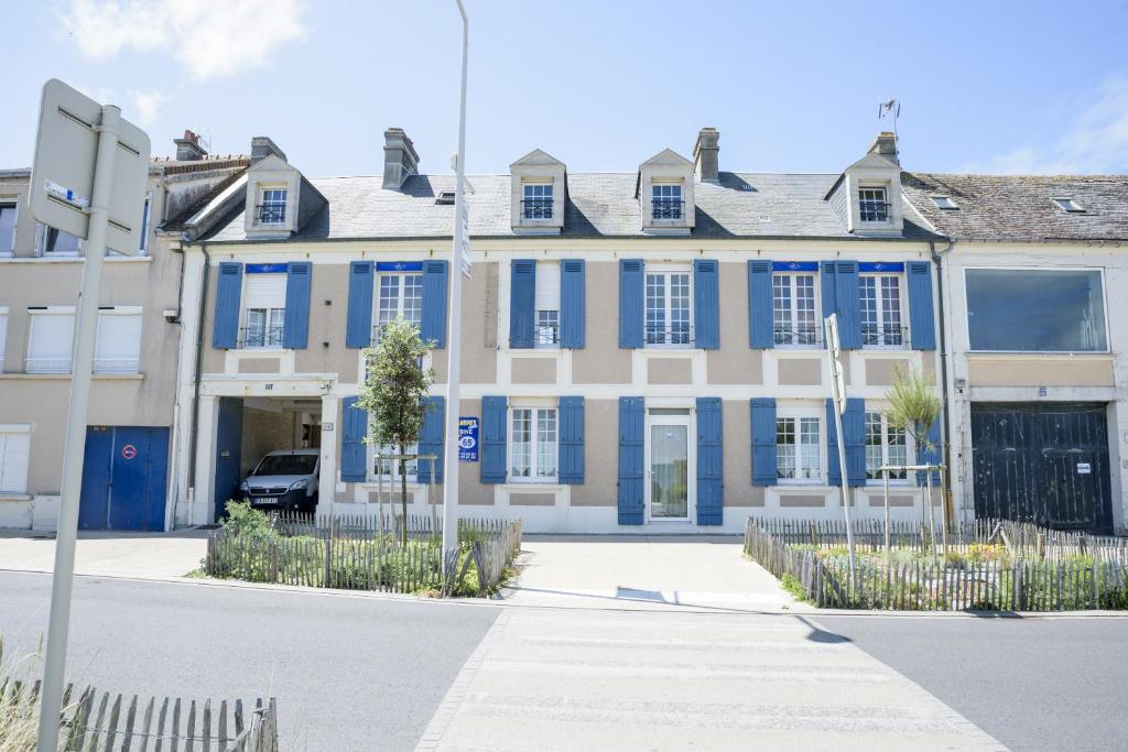 a blue and white building with blue shutters at Les quatre vents in Luc-sur-Mer