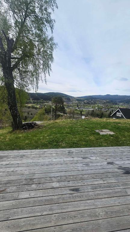 a wooden deck with a tree and a house at Leilighet med 2 soverom in Storen
