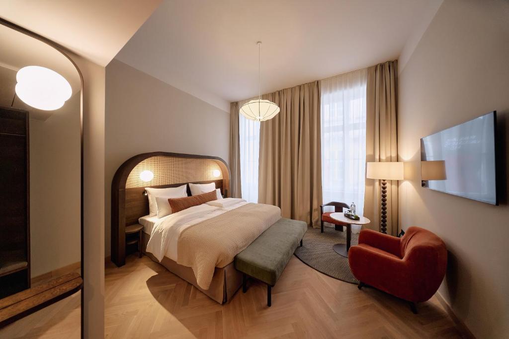 a hotel room with a bed and a red chair at Hotel Palais Mailberger Hof in Vienna