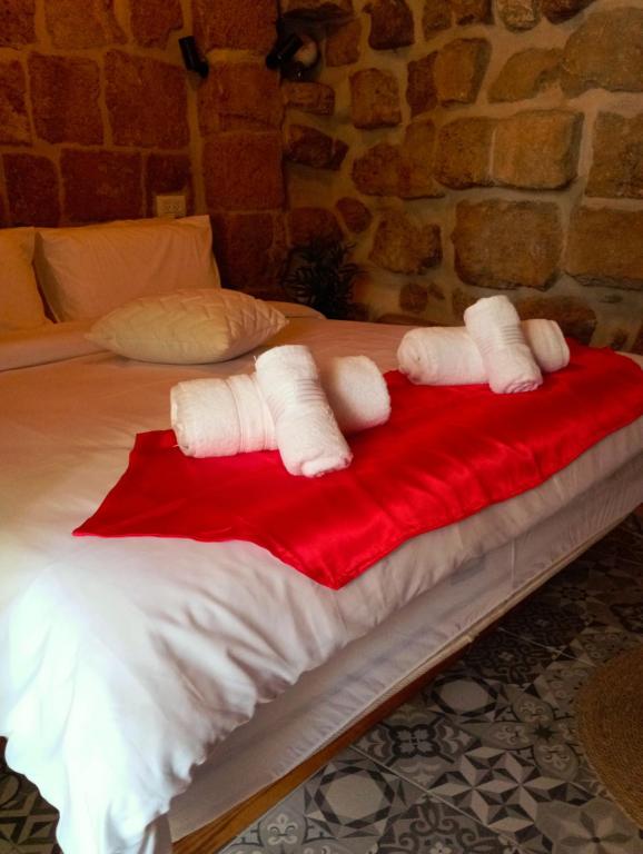 a bed with white towels on a red blanket at Calamari Suite in Acre