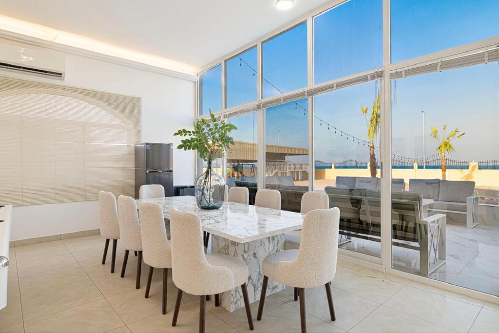 a dining room with a white table and chairs at Best chalet 4 BHK for group gatherings with beach access and private pool in Fujairah