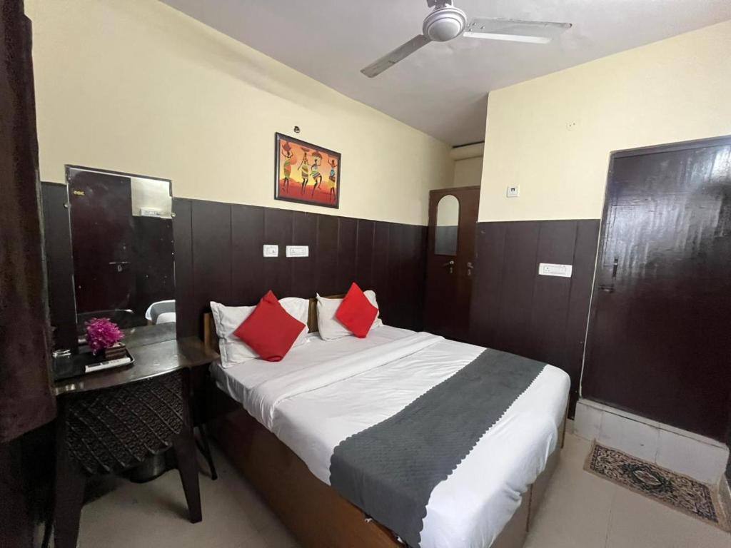 a bedroom with a bed with red pillows and a desk at Hotel South embassy near Durgabai dekhmukh metro in New Delhi