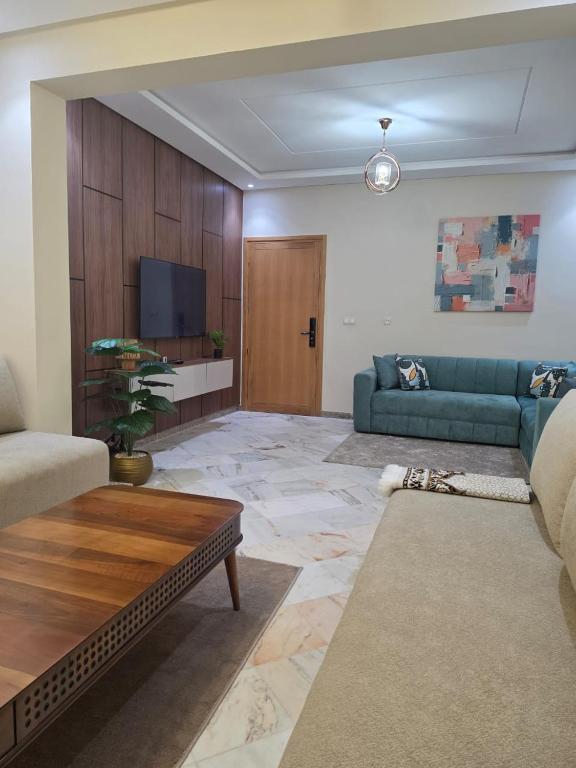 a living room with a blue couch and a tv at App najoua in Safi