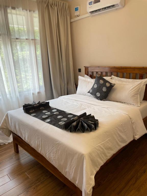 a bedroom with a large bed with white sheets and pillows at Peak Park Hotel in Mbeya
