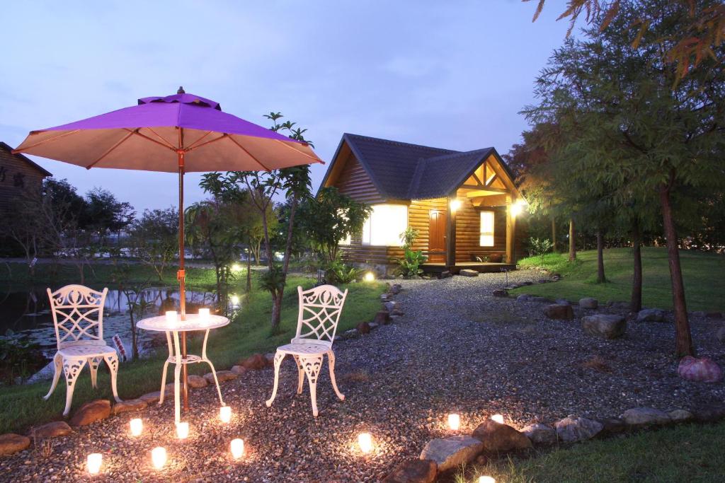 a table and two chairs with an umbrella and lights at Green Forest Villa in Yilan City