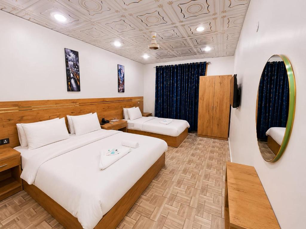 a hotel room with two beds and a mirror at Amada Family Guest House in Karachi