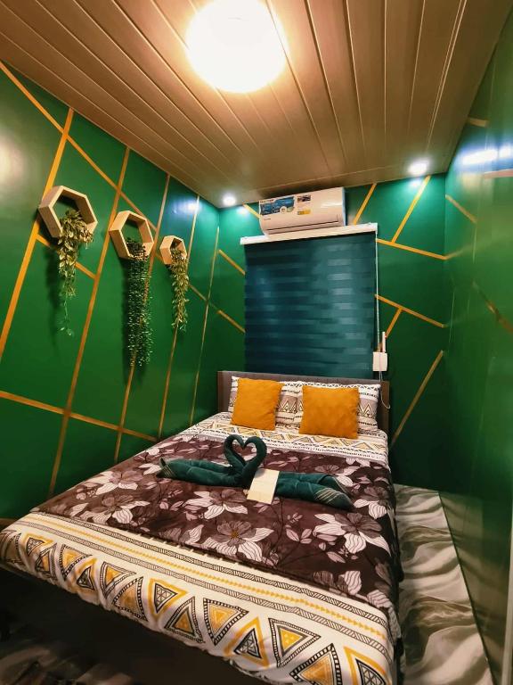 a bedroom with a bed with a green wall at Marcus Tiny House - Matcha in Cabanatuan City in Bangad