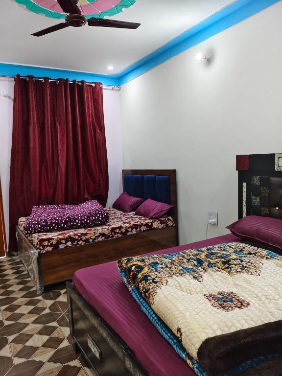 a room with three beds and a ceiling fan at HIMALAYAN ESCAPE HOMESTAy in Sari