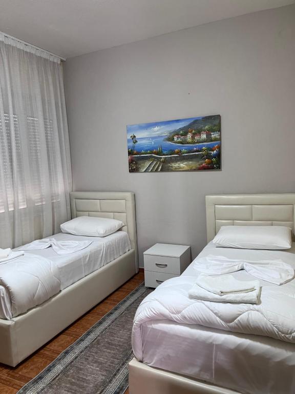 a bedroom with two beds and a painting on the wall at Vila Beliz in Tirana