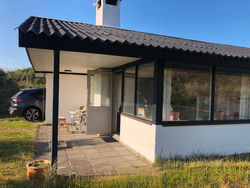 a small white house with a black roof at Sommerhuset i Saltum in Saltum
