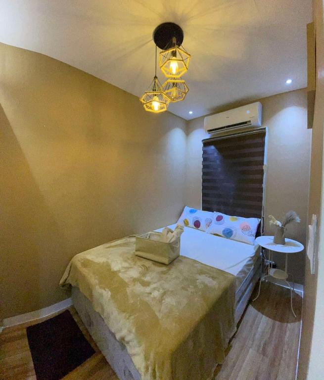 ein Schlafzimmer mit einem Bett, einem Tisch und einer Lampe in der Unterkunft Marcus Tiny House - Aesthetic in Cabanatuan City in Bangad