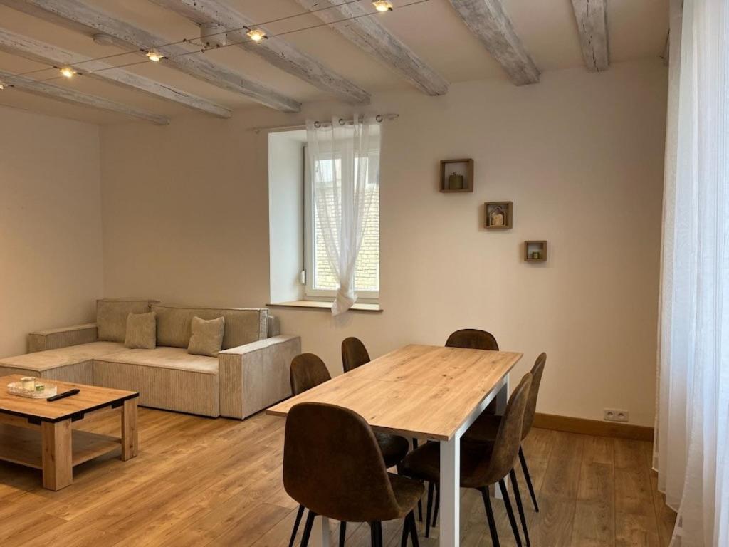 a living room with a table and a couch at Maison de Village in Leuglay
