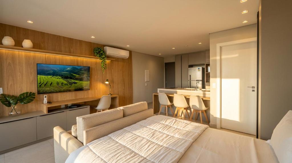 a living room with a bed and a kitchen at Facilidade no Coração da Cidade in Campo Grande
