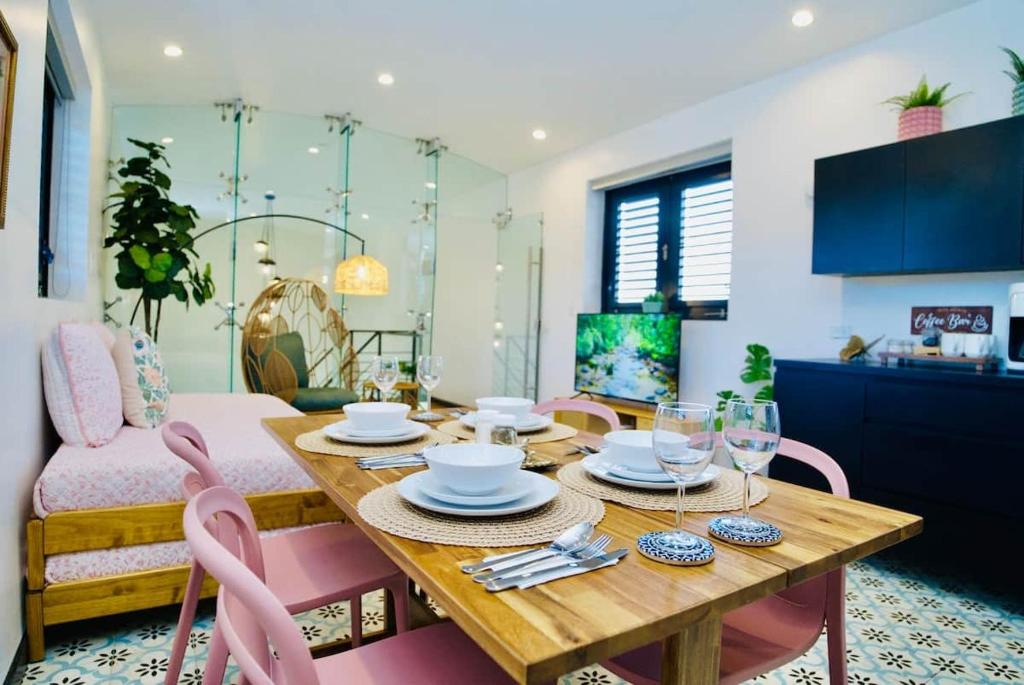 a dining room with a wooden table and pink chairs at 5.7 Penthouse • Generator • Parking • 3rd floor in Mayaguez