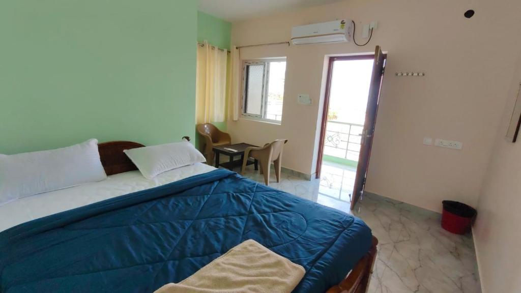 a bedroom with a bed and a table and a window at Ronazio Beach View Residency in Auroville
