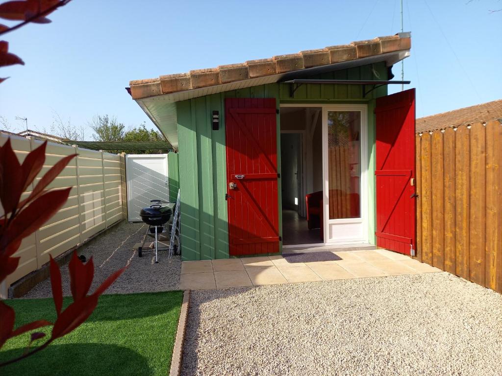 a green and red shed with a red door at Le Marsalat - Lanton in Lanton