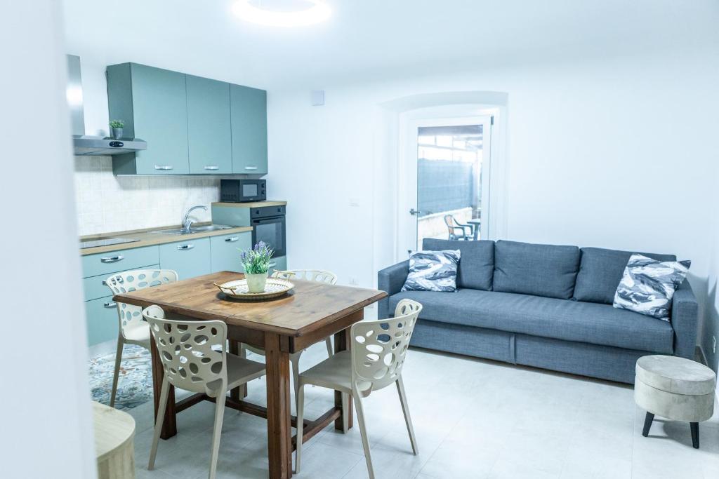 a kitchen and living room with a table and a blue couch at Cerenea House BiancAntò in Isola del Liri