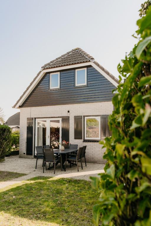 a house with a table and chairs in front of it at Vakantiehuis dicht bij het strand in Ouddorp