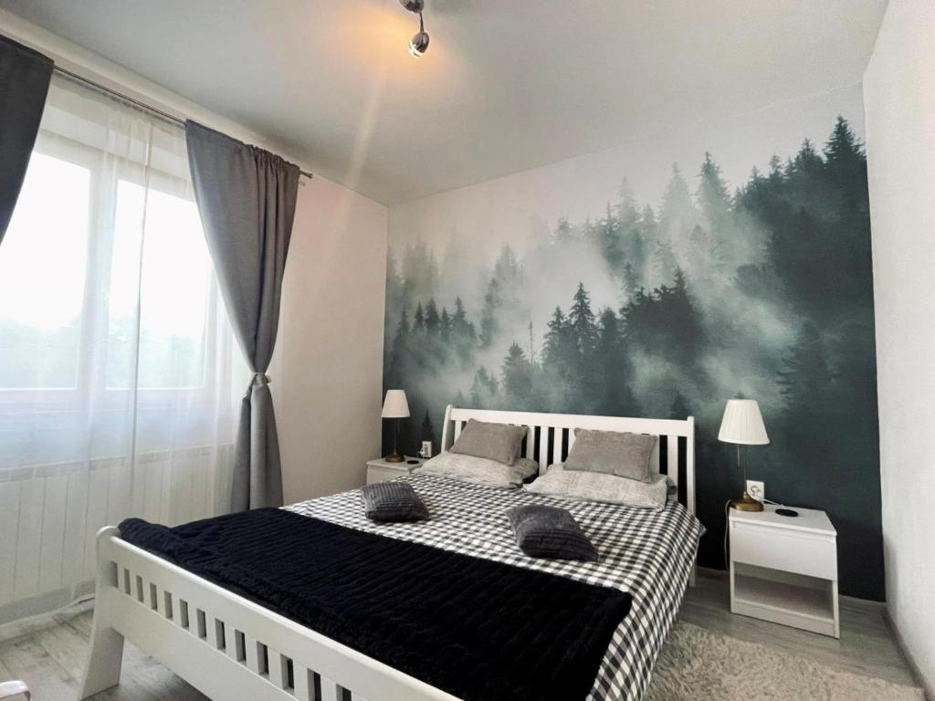 a bedroom with a bed with a forest mural on the wall at Waterfall apartment in Plitvička Jezera