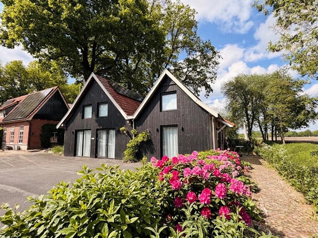 a black house with pink flowers in front of it at Bommartini Guesthouse in Enschede