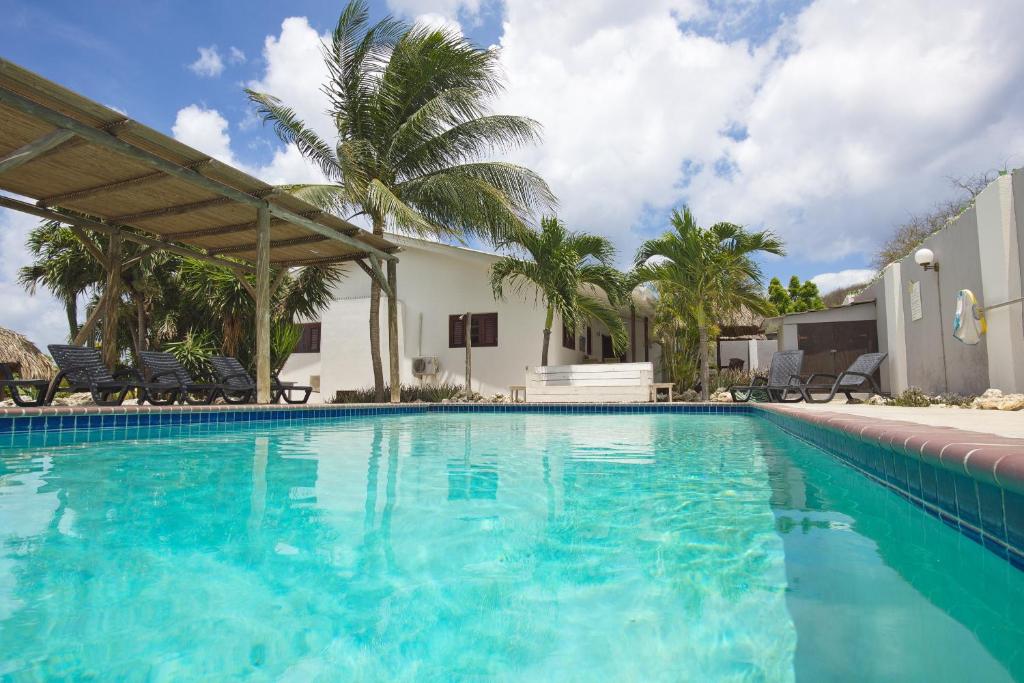 una piscina de agua azul frente a una casa en Bantopa Apartments, en Willemstad