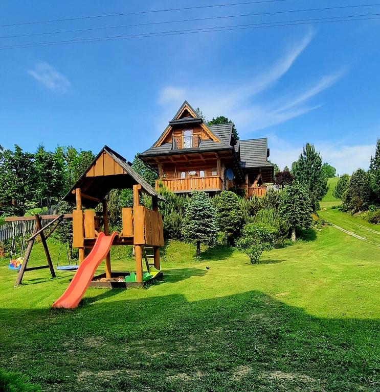 a large wooden house with a slide and a playground at Domek Kojsówka in Witów