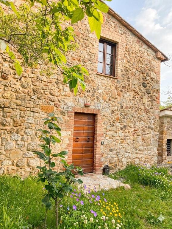 a brick building with a wooden door in a yard at Podere Santa Benedetta camera in Ribolla