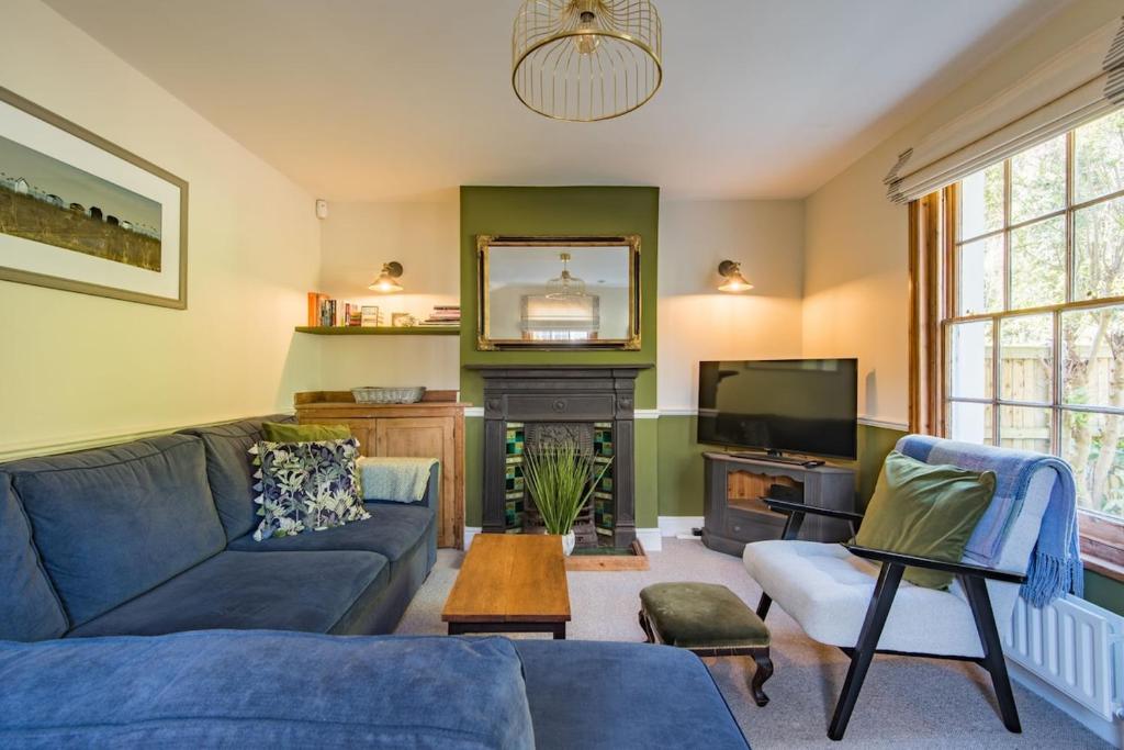 a living room with a blue couch and a tv at Pebble Beach Cottage by Keepers Cottages in Kingsdown
