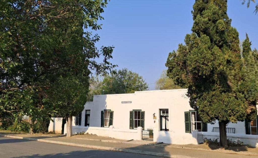 a white building with trees in front of it at Cypress Cottage - The Old House at River Bend in Graaff-Reinet