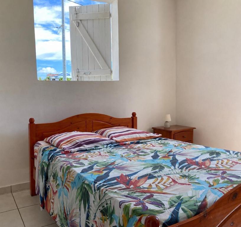 a bedroom with a bed with a colorful comforter and a window at Bel appartement à Damencourt in Le Moule