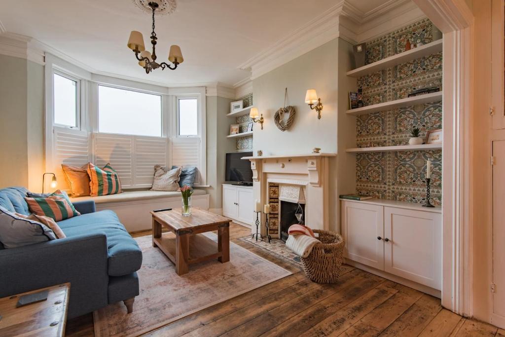 a living room with a blue couch and a fireplace at Whispering Waves by Keepers Cottages in Hythe