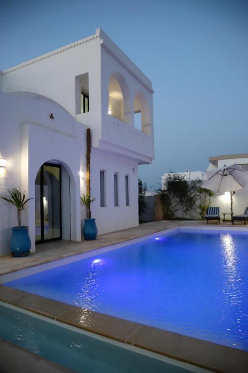 a villa with a swimming pool in front of a house at Villa l'olivier in Djerba