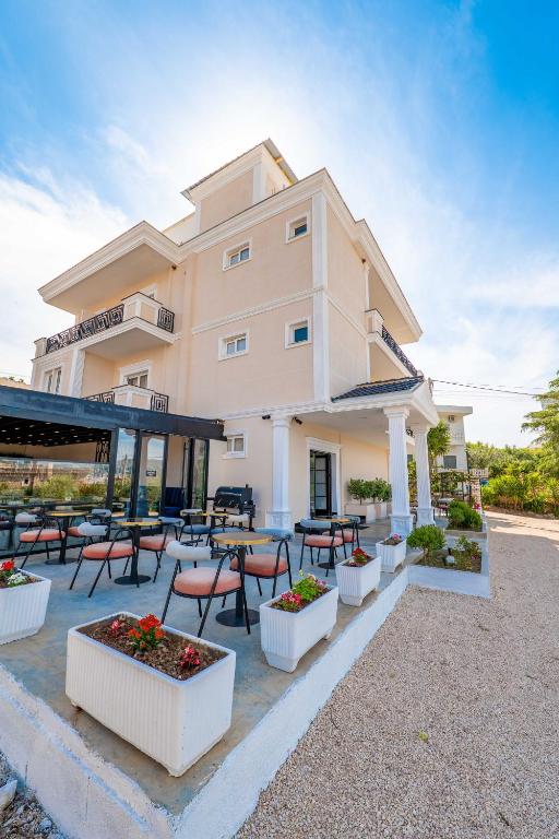 a building with tables and chairs in front of it at Hotel Almar in Sarandë