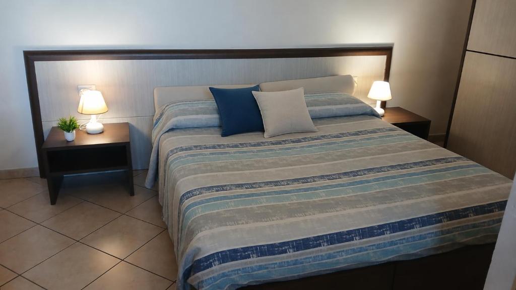 a bedroom with a large bed with blue and white pillows at Domo - Guest-House Il Nespolo Fiorito in Orosei