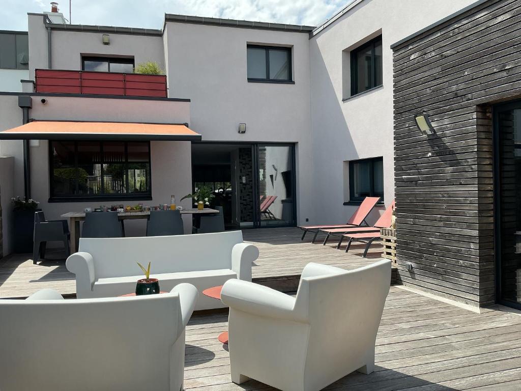 a patio with white furniture on a wooden deck at Chambres d'hôtes Ty Embruns in Larmor-Plage