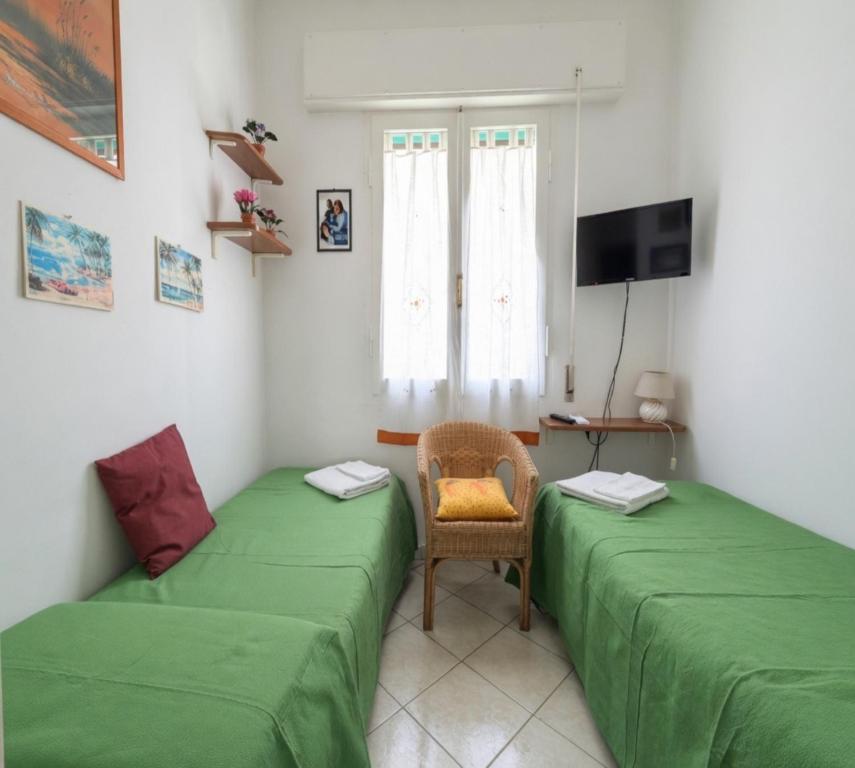 a room with two green beds and a chair at La stanza di Giuly in Porto Santo Stefano