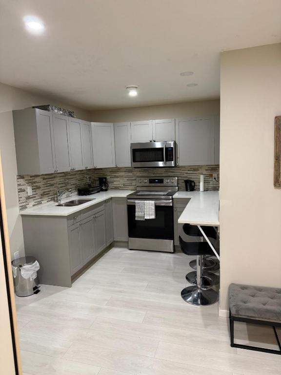 a kitchen with white cabinets and a stove top oven at The Urban Nest 2 in Calgary
