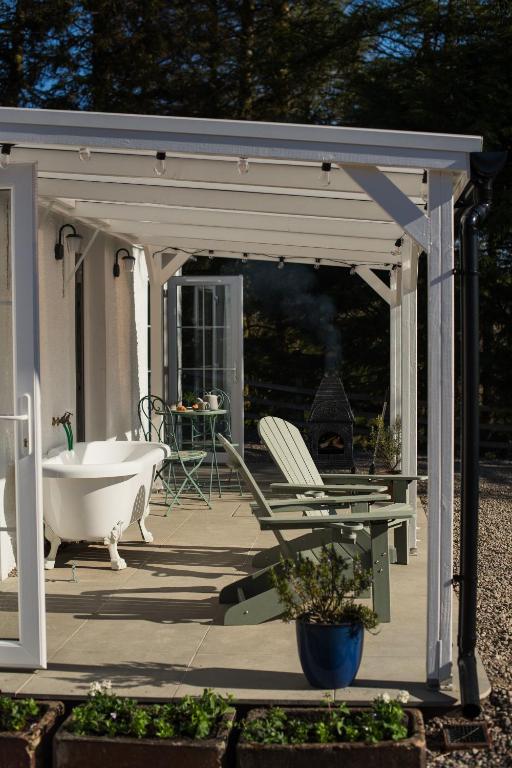 a white gazebo with a tub and a chair on a patio at Blacksheep Cottage in Oban