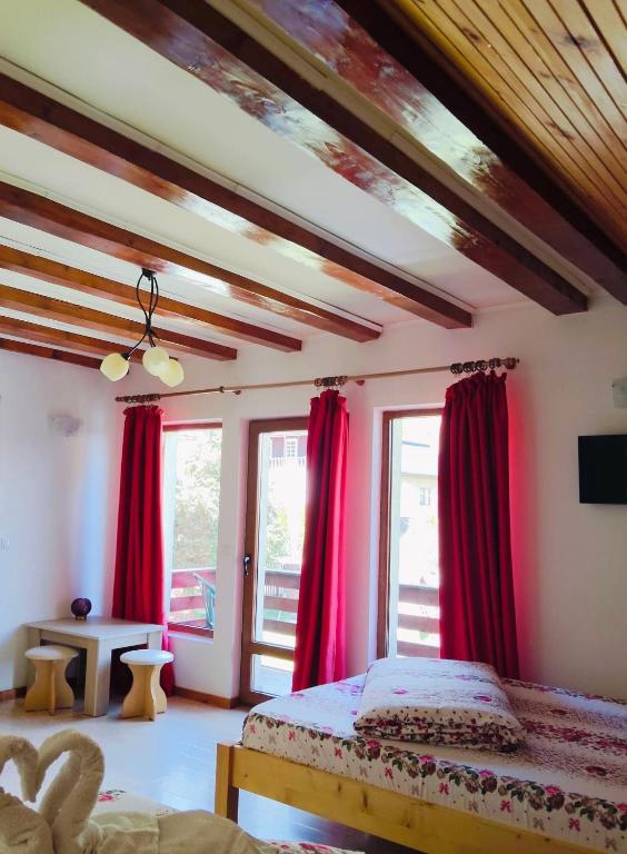 a bedroom with red curtains and a bed at Casa Silvia in Gârda de Sus