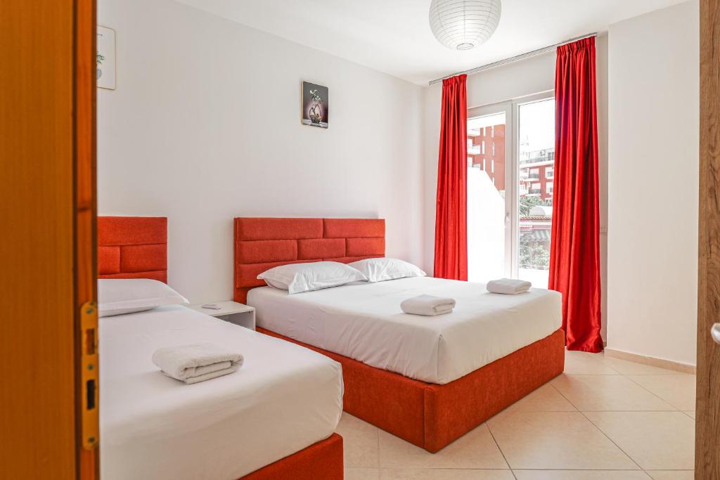 two beds in a bedroom with red curtains at Hotel Maresol Accommodation in Shëngjin